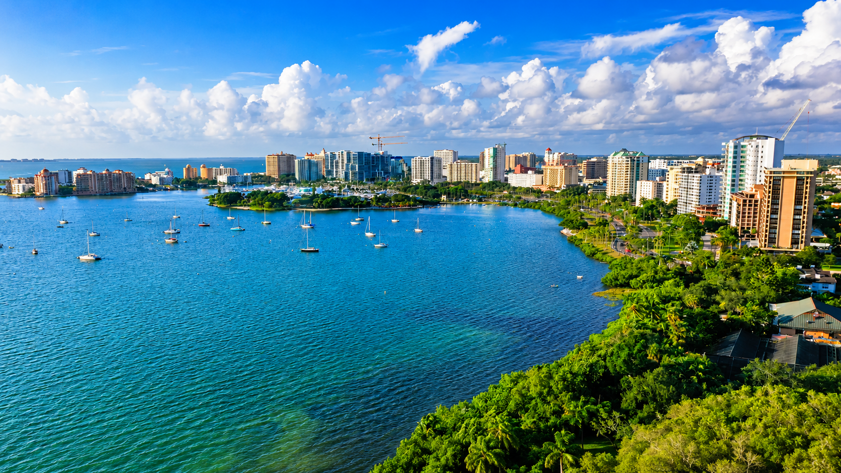 Aerial view of Sarasota waterfront with boats, skyline, and tropical coastline